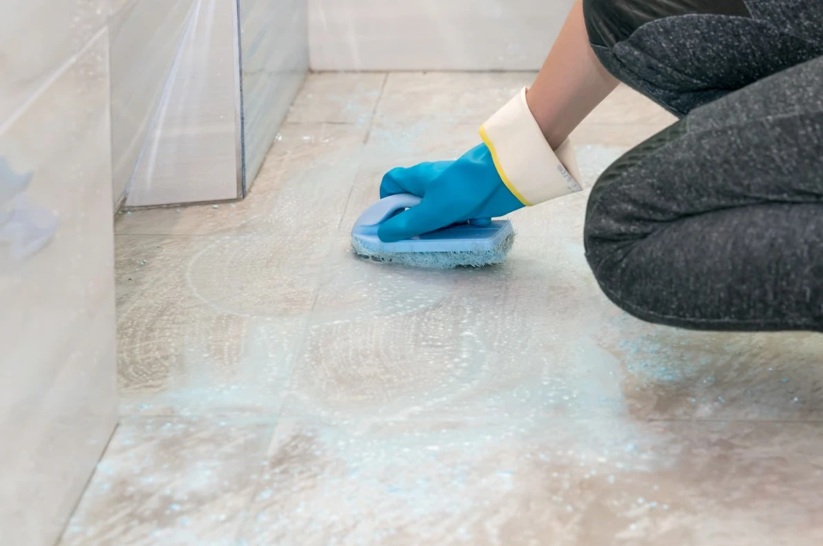 Person Cleans Bathroom Floor with Brush and Soap